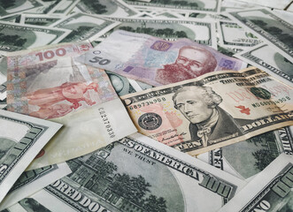 Several US dollars and Ukrainian hryvnia bills. The concept of cheapening and depreciation, increase and growth of exchange rates. The war in Ukraine and the budget.