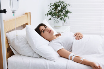 Young woman with intravenous drip in hospital bed