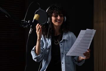 Singer wearing headphones recording song in professional studio