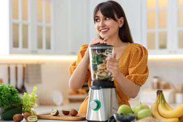Young woman making delicious smoothie with blender at white marble table in kitchen