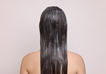 Naklejka premium Woman with applied hair mask on light background, back view