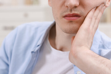 Man suffering from toothache at home, closeup