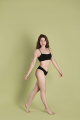 Fototapeta premium Woman with slim body posing on olive background