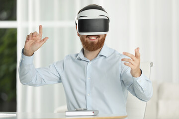Smiling man using virtual reality headset at workplace in office