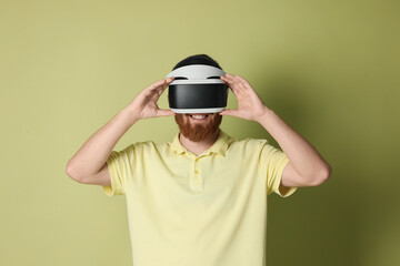Smiling man using virtual reality headset on pale green background