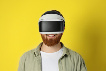 Smiling man using virtual reality headset on pale yellow background