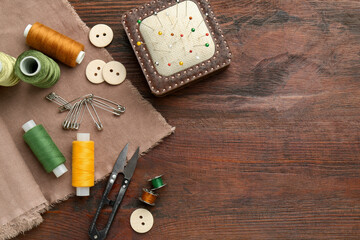 Flat lay composition with different sewing supplies on wooden table. Space for text