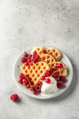 Homemade waffles with summer berries and a scoop of ice cream in plate on grey table with text space. Heart shaped waffles