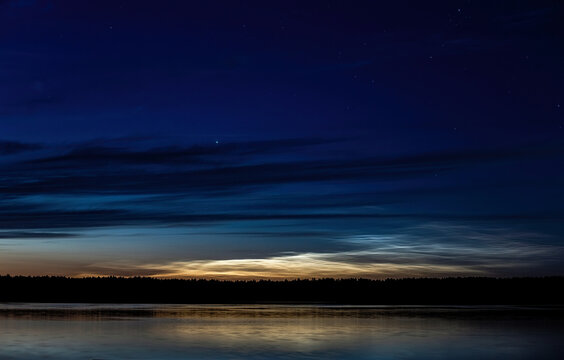 Lake at night, sky with stars, reflection in water, noctilucent clouds