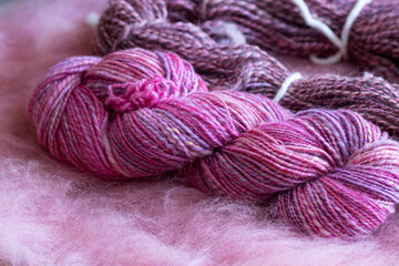 Rosa und lila per Hand gefärbte und gesponnene Wolle auf einem rosa Batt.