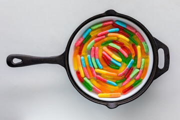 A frypan with colourful gummy worms in a spiral.
