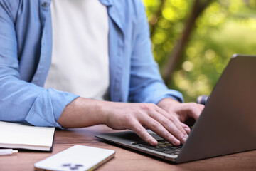 Freelancer working with laptop at table outdoors, closeup. Remote job