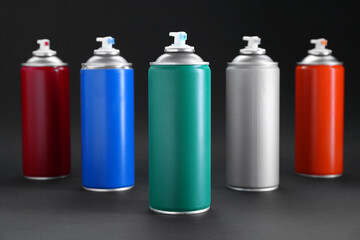 Many spray paint cans on dark gray background