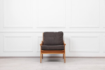 One comfortable soft armchair near white wall