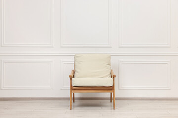One comfortable soft armchair near white wall