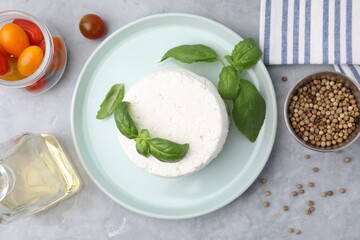 Fresh ricotta (cream cheese) and basil on gray table, flat lay