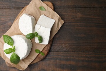Fresh ricotta (cream cheese) and basil on wooden table, top view. Space for text