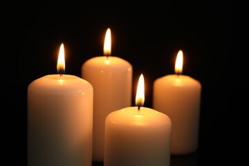 Many burning candles on black background, closeup