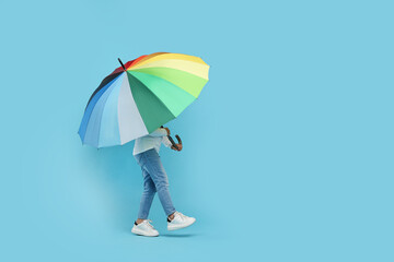 Little girl with colorful umbrella on light blue background. Space for text