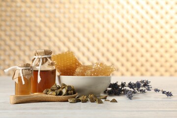 Natural honey tincture, lavender, propolis granules and sweet honeycombs on white wooden table