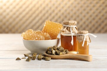 Natural honey tincture, propolis granules and sweet honeycombs on white wooden table
