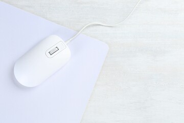 Computer mouse with mousepad on light wooden table, top view. Space for text