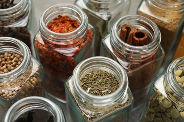 Different spices in glass jars on table, closeup