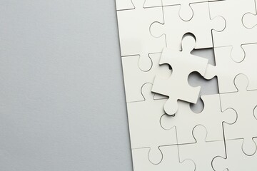 White puzzle pieces on grey background, top view. Space for text