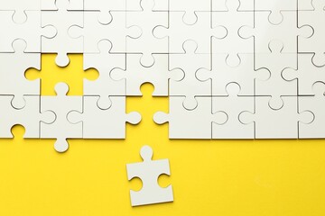 White puzzle pieces on yellow background, top view