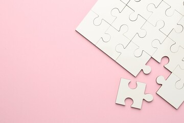 White puzzle pieces on pink background, top view. Space for text