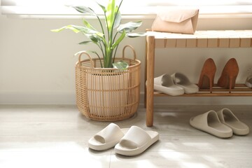 Many pairs of slippers and other shoes in entryway at home