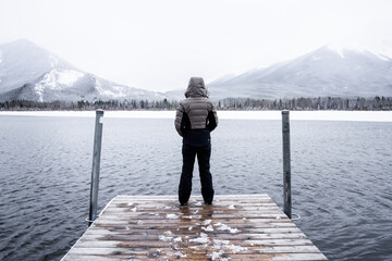 Girl standing on dock overlooking a partially thawed Vermillion Lake in Banff National Park.