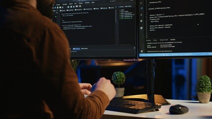Software engineer typing on keyboard buttons, writing lines of code in apartment office. Close up...