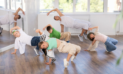 Happy girl and teens doing breakdance in dance hall with male trainer in light choreography studio