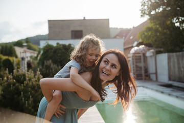 Mom giving her little son piggyback ride in the garden. Bonding between mother and child, Concept...