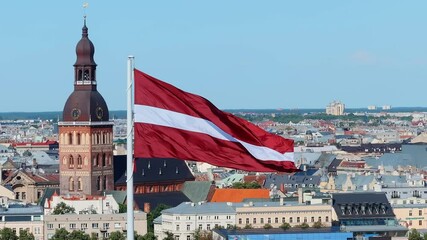Latvian national flag waving with old Riga cityscape in the background