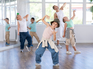 Fototapeta premium Group of teen children participating hip hop dance in class, following their teacher in modern dance school