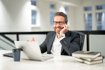 Obraz premium Business man talking on phone at office workplace. Hispanic business man using laptop. Millennial man using laptop at office workplace. Ceo manager office worker business people working at office.