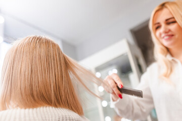 Obraz premium Stylist Combing Blonde Hair in Salon