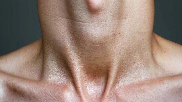 A quick closeup of a persons neck as they visibly swallow and tremble goosebumps forming along their throat and jawline.