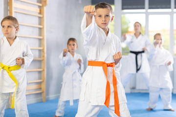 Kata karate teacher conducts classes and performs movements and fighting techniques together with boys and girls students to prepare them for competitions.