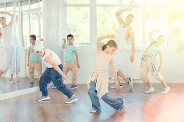 Young boys and girls in casual wear performing hip hop at group dance class in choreographic studio