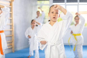 Obraz premium In gym, certified master coach conducts karate kata lesson with children boys girls team students group and shows sequence of actions when conducting close fight
