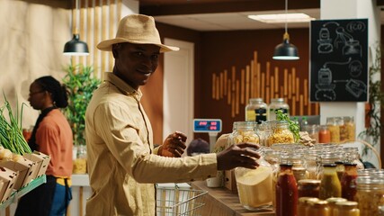 Client examines cereals and grains at zero waste eco store, looking for natural organic products...