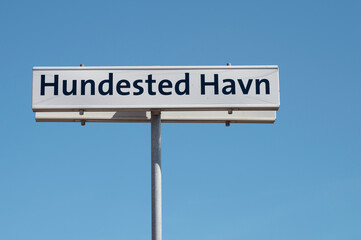 wooden sign that says Hundested harbor against a blue sky, Denmark, July 21, 2024
