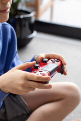 The boy holds a joystick in his hand and is intently playing a video game. Video games.