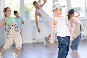 Fototapeta premium Portrait of confident happy tween boy hip hop dancer training during group dance class in modern dance studio