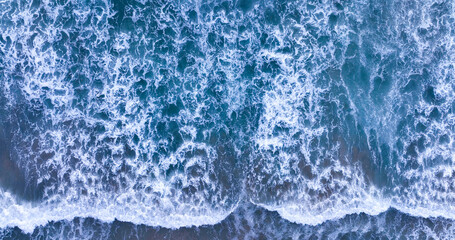 Top view of summer sea waves. Blue sea water in sunny day. Aerial view from drone. Amazing tropical nature background. Tranquil sea waves splashing on sand beach.