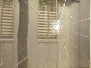 Broken window with a reflection of other windows and a tree