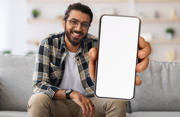 Cheerful Indian Guy Showing Smartphone With Big Blank White Screen At Camera, Happy Young Eastern...